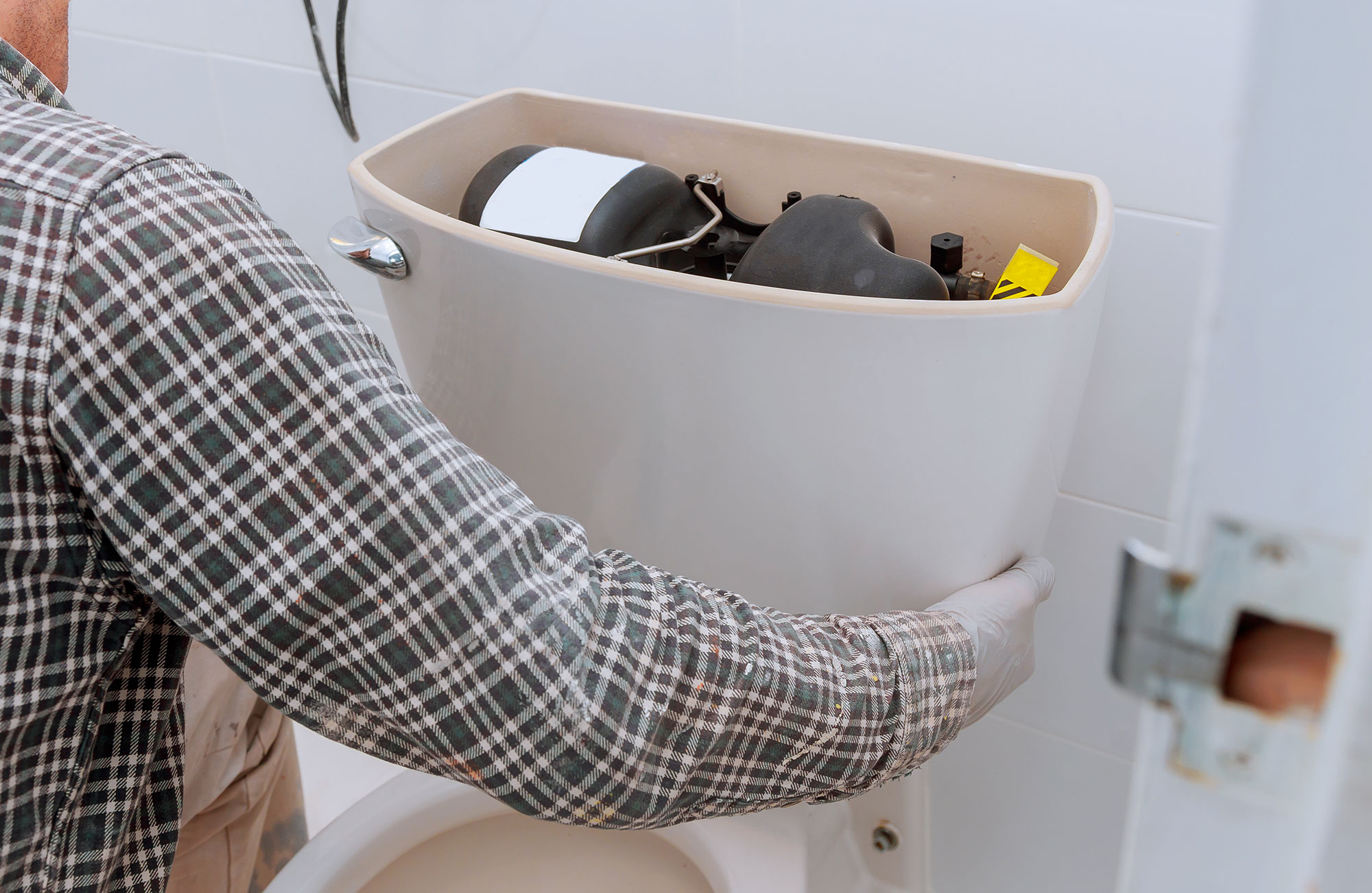 man installing a tank onto a toilet